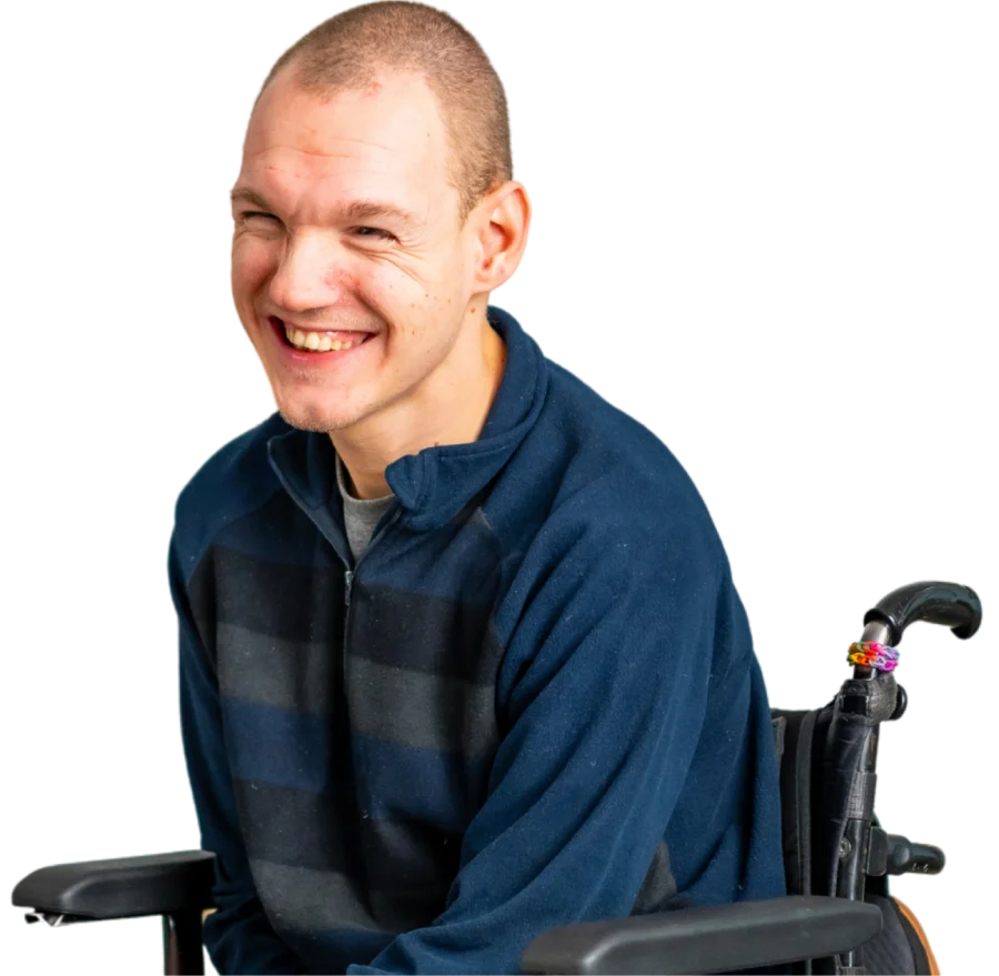 Smiling man in a dark striped sweater sitting in a wheelchair against a transparent background.